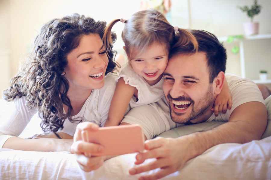 Gothaer Auslandskrankenversicherung für Familien: Eine glückliche Familie macht ein Foto mit einem Handy.