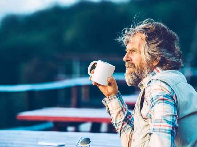 Pflegetagegeldversicherung: Älterer Herr trinkt eine Tasse Kaffee auf einer Terrasse.